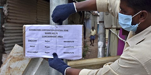A Corporation staff displaying the contact numbers for essential services at a locality which has been declared as containment zone, in Coimbatore. (Photo| U Rakesh Kumar, EPS)