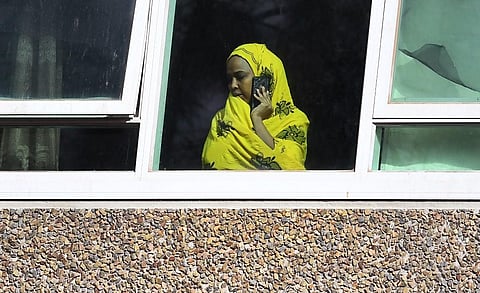 A resident looks from a window at one of nine public housing estates locked down due a spike in coronavirus numbers in Melbourne (Photo| AFP)