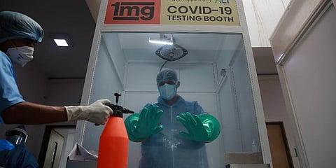 A health worker sanitises the gloves of another inside a booth after he collecting samples for COVID-19 test at Rajiv Gandhi Super Speciality hospital in New Delhi. (File Photo | Shekhar Yadav, EPS)