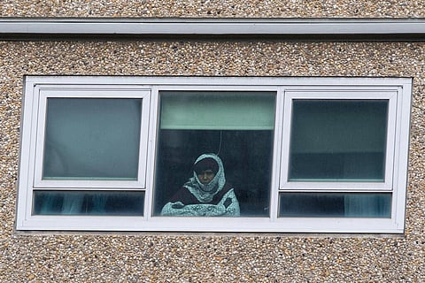 A woman looks out a window from a locked-down public housing tower in Melbourne, Monday, July 6, 2020. As Australia is emerging from pandemic restrictions, the Victoria state capital Melbourne is buckling down with more extreme and divisive measures that