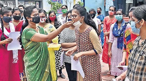 A teacher offering sweet to students of class X after distributing marksheets at a private school in Chennai on Monday | P Jawahar
