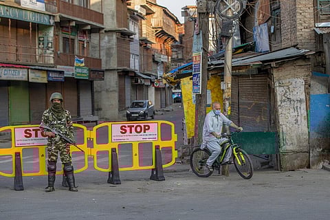 A Kashmiri man on cycle goes past a barricade set up as road blockade as a paramilitary soldier stands guard in Srinagar (Photo | AP)