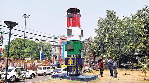 A man dyes a fabric on a pavement next to the smog tower (a 20-feet-tall air-purifier) at Lajpat Nagar. (Photo | EPS)