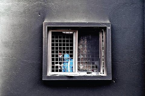 A health worker collects swabs from officers inside DJ Halli Police Station, in Bengaluru, which was set ablaze by a mob on Tuesday