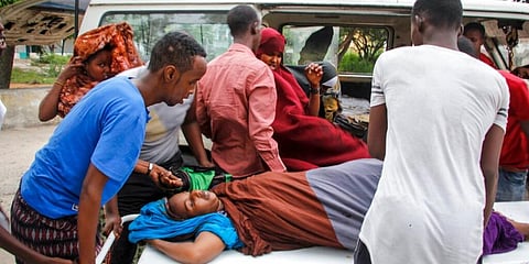 Medical workers and other Somalis help a woman who was wounded when a powerful car bomb blew off the security gates to the Elite . (Photo | AP)