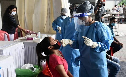 A health worker collects a swab sample from a woman for Covid-19 rapid antigen testing at Anand Vihar bus terminal in New Delhi on Monday. (Photo | Parveen Negi/EPS)