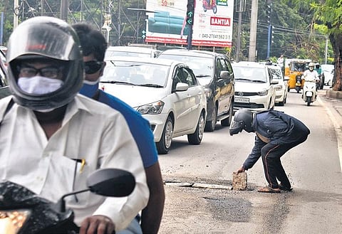 A motorist tries to fix a damaged road on his own using a brick, in Secunderabad. (Photo | S Senbagapandiyan, EPS)