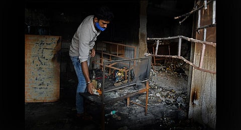 An owner of a liquor store inspects his shop after it was burnt down during the DJ Halli riots in Bengaluru. (Photo | Meghana Sastry, EPS)
