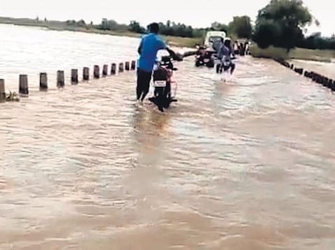 Commuters cross a submerged bridge on Gobindapur-Manapur road | EXPRESS
