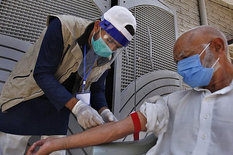 A health worker gets blood sample of a person during door-to-door testing and screening facility for the new coronavirus, in Islamabad, Pakistan. (File Photo | AP)