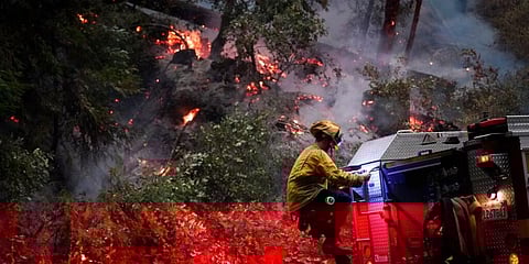 A firefighter for the Boulder Creek Fire Department, gets down from a fire truck along Highway 9 while monitoring flames. (Photo | AP)