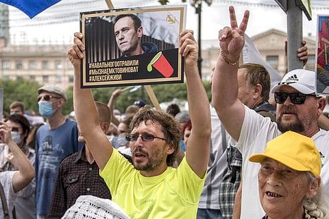 A man holds a poster with a portrait of Alexei Navalny reading 'Navalny was poisoned, we know who is to blame...' during an unsanctioned protest. (Photo | AP)