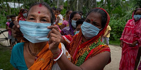 A woman helps another wear a mask as a precaution against the coronavirus. (Photo | AP)