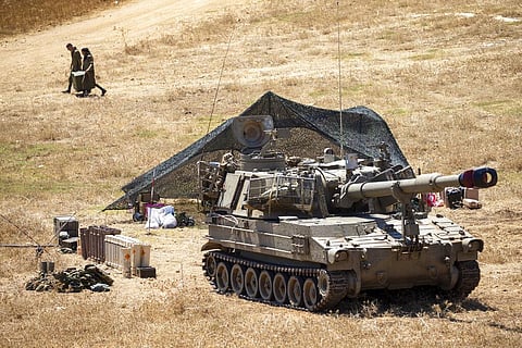 Israeli soldiers carry a box next to their mobile artillery piece near the border with Lebanon, northern Israel. (Photo | AP)