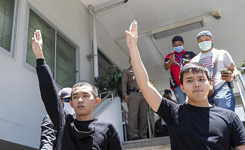 Panumas Singprom, left, and Tattep Ruangprapaikitseree raise a three-finger salute, a symbol of resistance, as they arrive at the Samranrat police station in Bangkok, Thailand. (Photo | AP)
