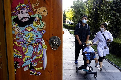 Residents wearing masks to curb the spread of the coronavirus walk on a Beijing street. (Photo | AP)