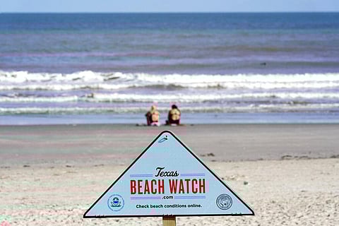 Beachgoers sit on the beach Tuesday, Aug. 25, 2020, in Galveston, Texas, as Hurricane Laura heads toward the Gulf Coast. (Photo | AP)