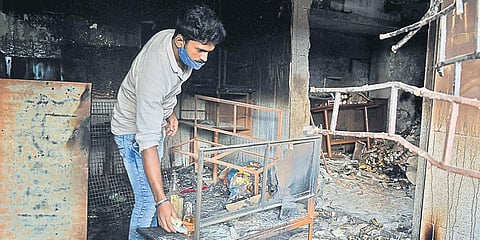 An owner of a liquor store inspects his shop after it was burnt down during the recent DJ Halli riots in Bengaluru.