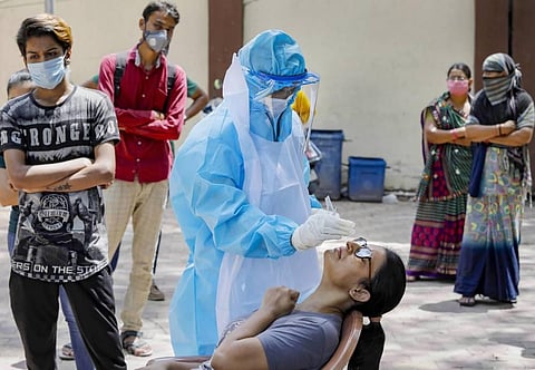 A healthcare worker wearing a PPE kit takes a sample of a woman for COVID-19 test at a residential area in Ahmedabad Wednesday July 8 2020. (Photo | PTI)