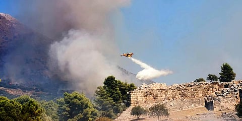 A plane drops water during a wildfire in the ancient site of Mycenae, Greece, some 140 kilometers south of Athens. (Photo | AP)