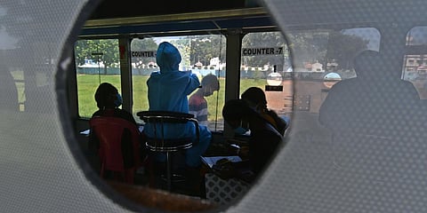 A health worker sits in a bus and collects samples to get them tested for coronavirus, in Vijayawada on Sunday. (Photo|Prasant Madugula, EPS)