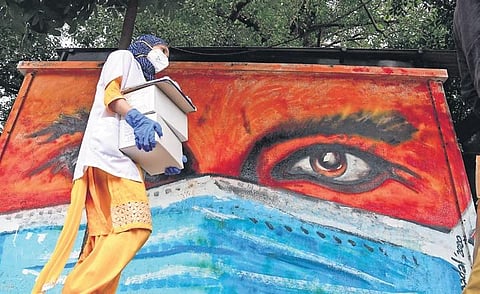 A health worker carries coronavirus testing kits to a clinic near Town Hall Junction in Bengaluru on Tuesday | SHRIRAM BN