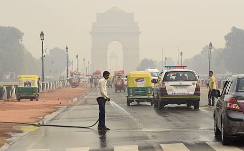 A worker sprays water on a road under heavy smog conditions in New Delhi. (File photo| Parveen Negi, EPS)