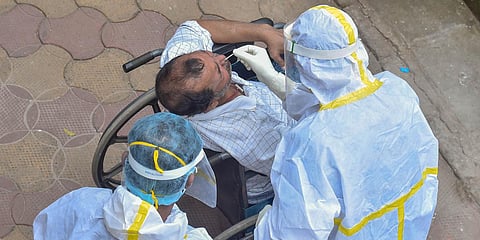 A medic collects samples from a physically disabled person amid the complete bi-weekly lockdown to curb COVID-19 spread in Kolkata. (File photo| PT)