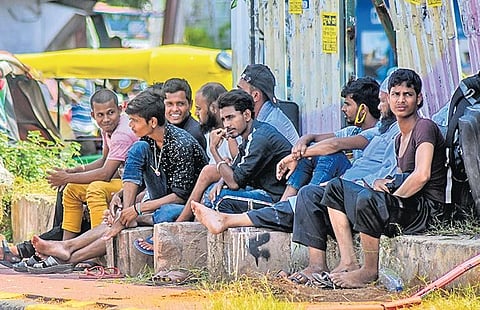 A group of youths sits without masks and social distancing near Station Square in Bhubaneswar on Wednesday. (Photo | EPS)