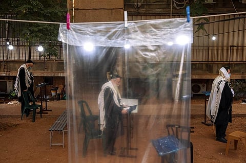 Ultra-Orthodox Jews keep social distancing, wear face masks during a morning prayer next to their houses as synagogues are limited to twenty people in Israel. (Photo | AP)