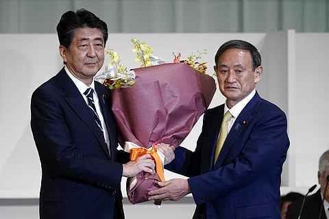 Japan's Prime Minister Shinzo Abe, left, receives flowers from Chief Cabinet Secretary Yoshihide Suga after Suga was elected as new head of Japan's ruling party. (Photo | AP)