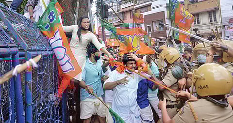 A policewoman tries to pull down a Yuva Morcha worker as she climbs atop a police barricade near the north gate of the Secretariat in T’Puram during a protest demanding the resignation of Higher Educa
