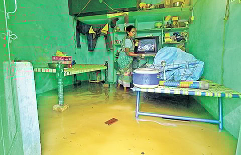 A woman taking away household goods as floodwater enters her home, at Rani Gari Thota in Vijayawada on Tuesday | Prasant Madugula