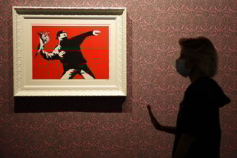 A worker walks past 'Love Is in the Air', a screen print on paper, by British artist Banksy, a day before the unveiling of an exhibition in Rome. (Photo | AP)