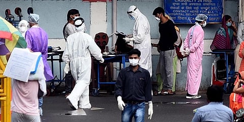 Medical workers in PPE gear interacting with visitors outside the COVID-19 ward at AIIMS Hospital in New Delhi.