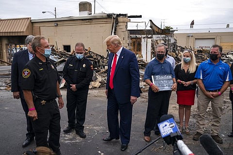 President Donald Trump speaks with business owners and law enforcement officials as he tours an area damaged during demonstrations after a police officer shot Jacob Blake in Kenosha. (Photo | AP)