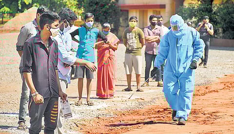 A sanitation worker sprays disinfectant at a queue for Covid test in Vijayawada on Wednesday I Prasant Madugula