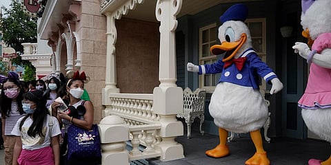 Visitors wearing face masks line up to take photos with the iconic cartoon characters Donald Duck and Daisy Duck at the Hong Kong Disneyland. (Photo| AP)