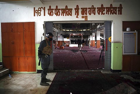 A policeman stands guard at the entrance to a Sikh house of worship as journalists film the aftermath of an attack in Kabul. (File photo | AP)