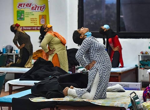Patients perform yoga at CWG village COVID-19 Care Centre near Akshardham in New Delhi Sunday Sept. 27 2020. (Photo | PTI)