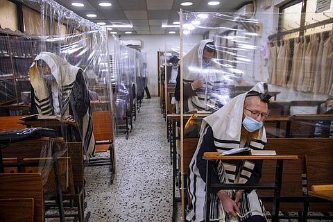 Ultra-Orthodox Jews wear face masks during a morning prayer in a synagogue separated by plastic partitions, in Bnei Brak, Israel. (Photo | AP)