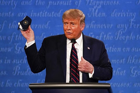 US President Donald Trump holds up his face mask during the first presidential debate Tuesday, Sept. 29, 2020, at Case Western University and Cleveland Clinic, in Cleveland, Ohio. (Photo | AP)