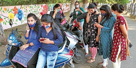 Students browsing mobile phones for their results in Bhubaneswar. (Photo | Irfana, EPS)
