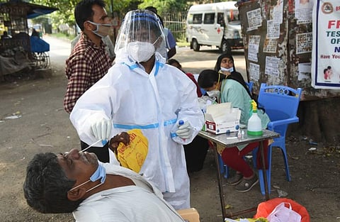 A health worker collects a nasal swab from a person to send it for COVID testing at city market near Victoria Hospita in Bengaluru on Sunday. (Photo | Nagaraja Gadekal/EPS)