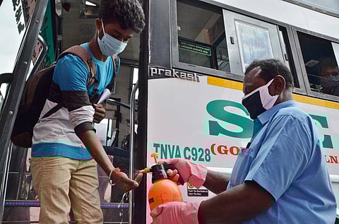 A bus conductor gives hand sanitizer to a passenger at Tirunelveli New bus stand. (Photo | EPS/ V Karthik Alagu)