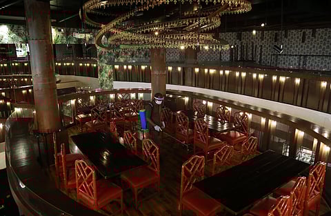 An employee wearing a face shield sanitizes a table inside QBA Bar ahead of resumption of alcohol servings to customers from September 9 in New Delhi. (Photo | EPS/Shekhar Yadav)
