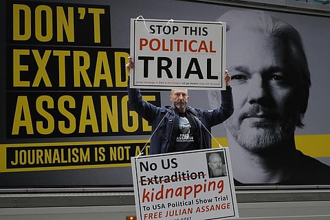 A demonstrator holds placards near the Central Criminal Court Old Bailey in London. (Photo | AP)