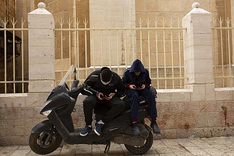 Young men scroll on their smart phones in the Old City of Jerusalem. (Photo | AP)
