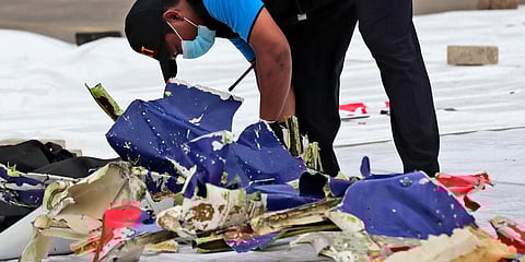 An investigator of Indonesian National Transportation Safety Committee inspects parts of Sriwijaya Air Flight 182 that crashed in the waters off Java Island. (Photo| AP)
