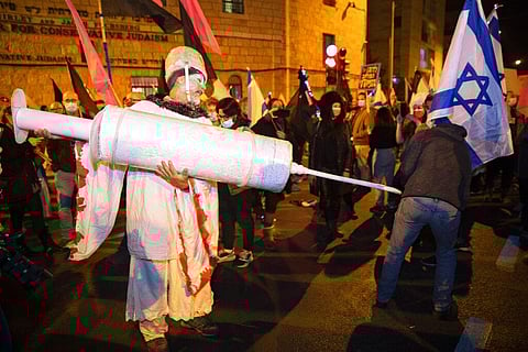 An Israeli protester holds a giant syringe during a demonstration against Israeli Prime Minister Benjamin Netanyahu. (Photo | AP)